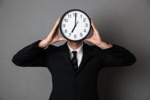 man holding a clock in front of his face
