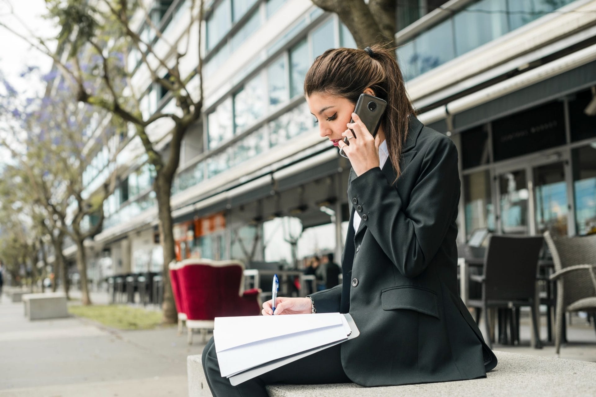 Businesswoman holding a pen and paper while on a call