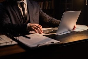 A man in a suit is focused on his laptop