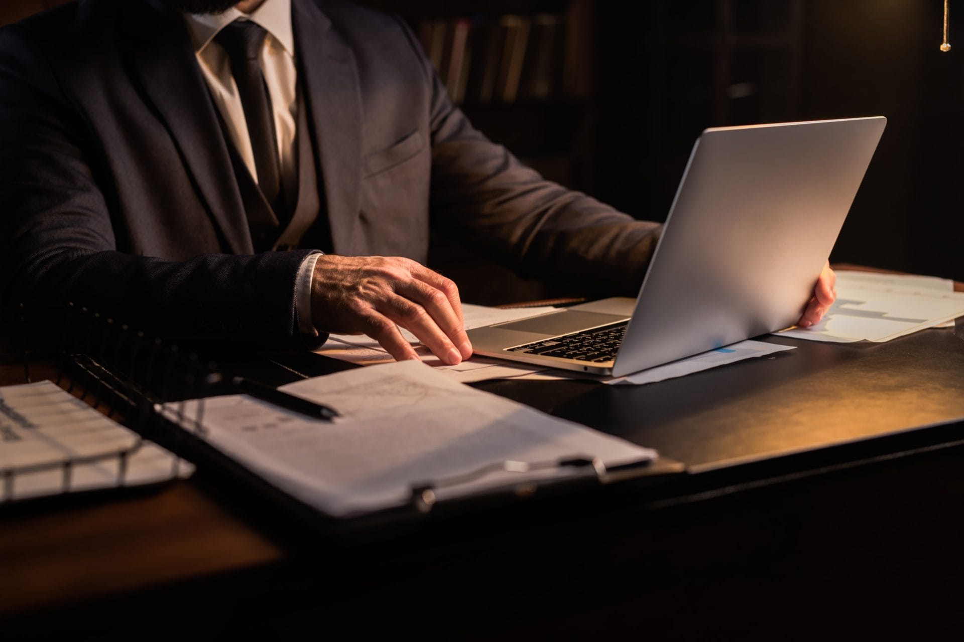 A man in a suit is focused on his laptop